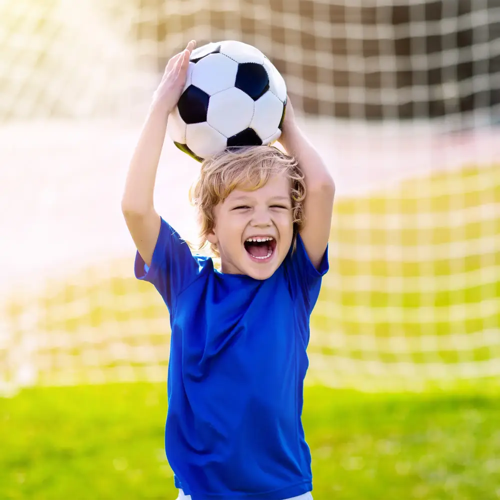A child holding a soccer ball overhead